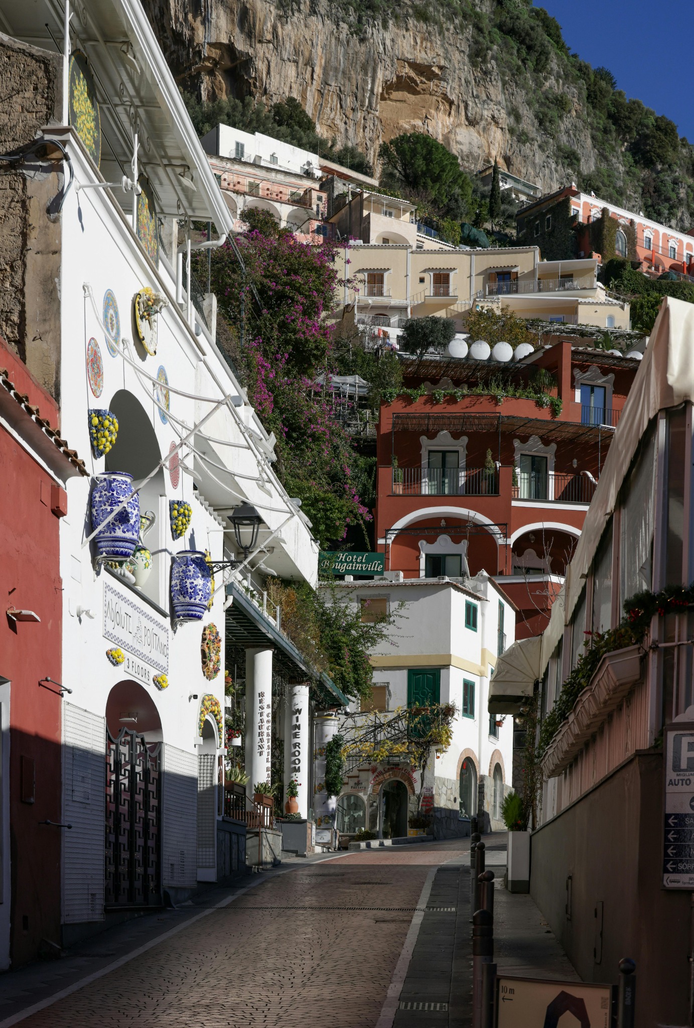 Amalfi Coast street scene with hillside buildings beneath dramatic cliffs